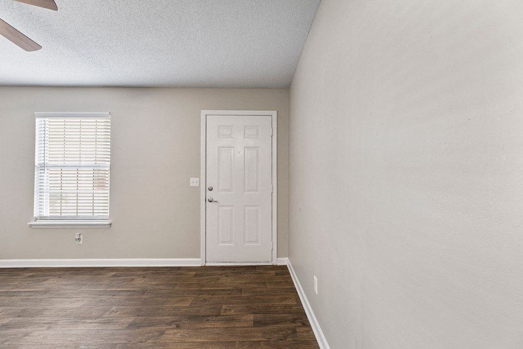 A room with a white door and a window with blinds.