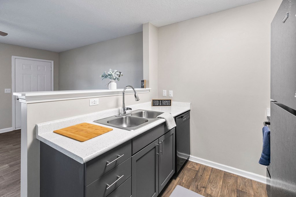 A kitchen with a white countertop and grey cabinets.