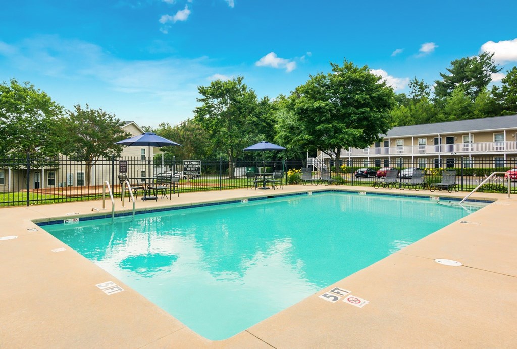 A large swimming pool surrounded by trees and apartment buildings.
