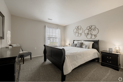 A bedroom with a large bed and a window with blinds.