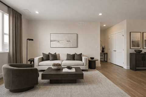 A modern living room with a grey sofa, a brown armchair, a coffee table, and a large painting on the wall.