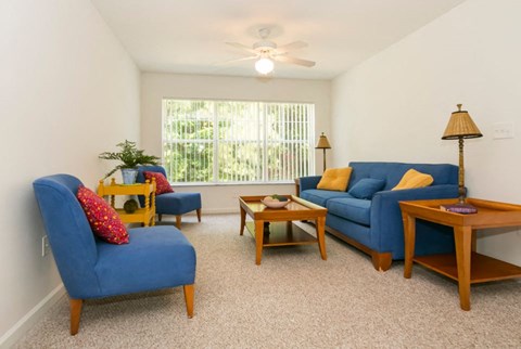 a living room with blue couches and chairs and a window