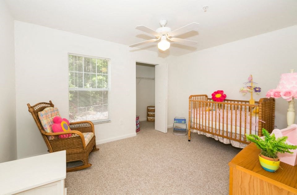 a nursery with a crib and a chair and a ceiling fan