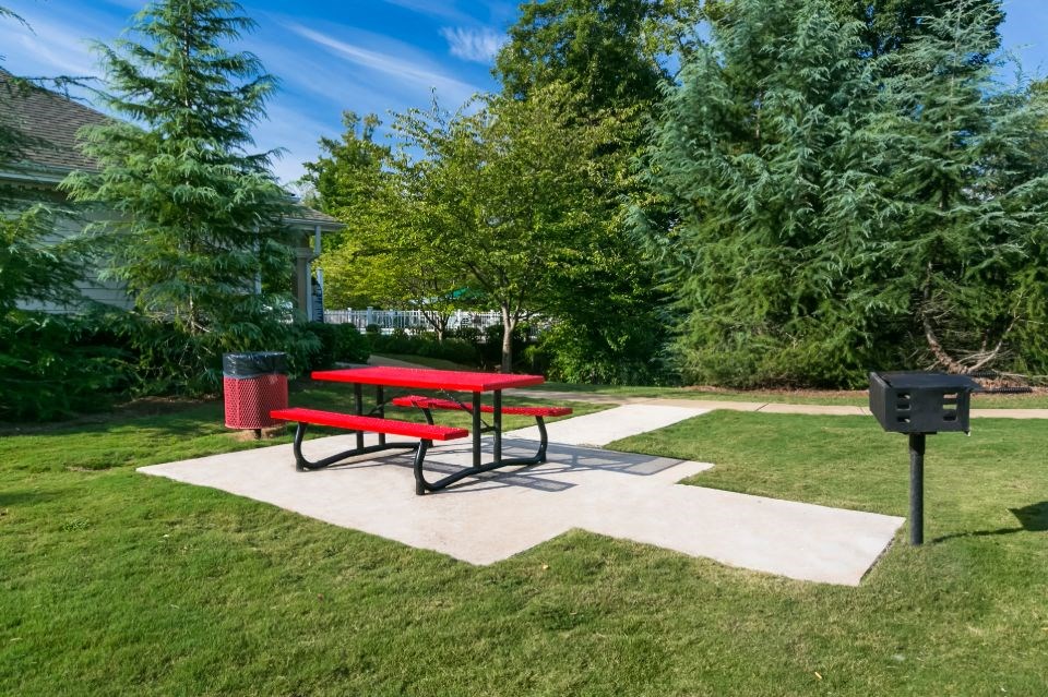 a picnic area with a red picnic table and a grill