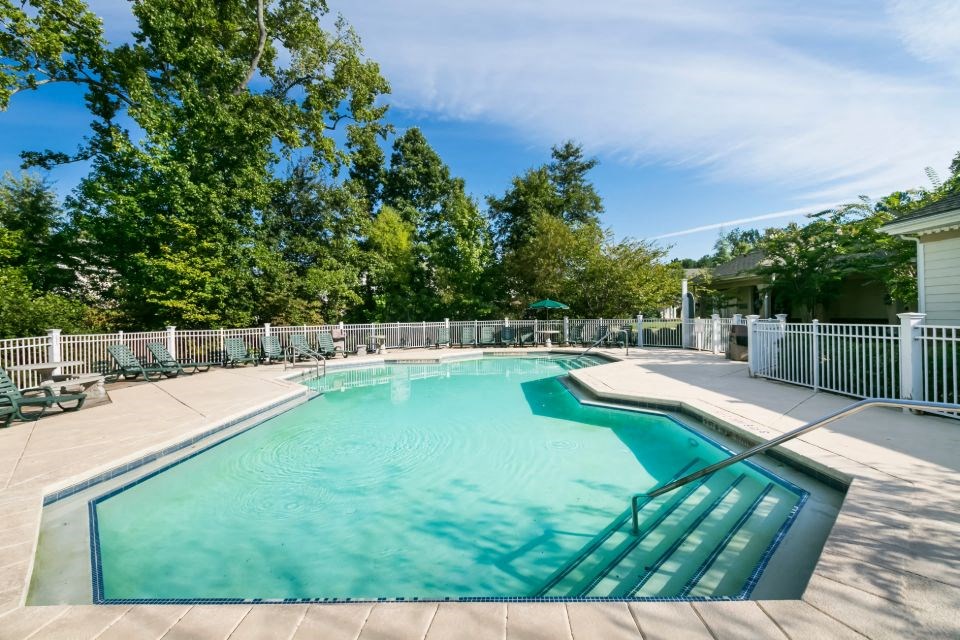 a resort style pool with a fence around it and trees