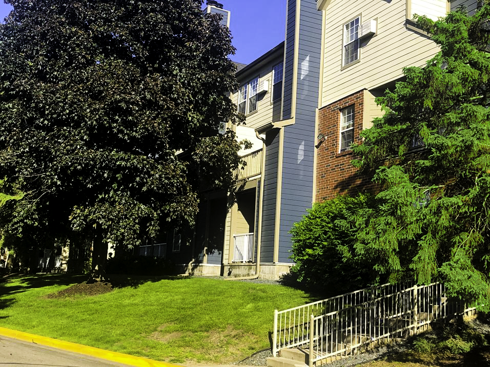 the front yard of an apartment building with a lawn and a fence
