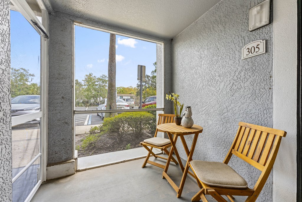 a porch with two wooden chairs and a small table and a window