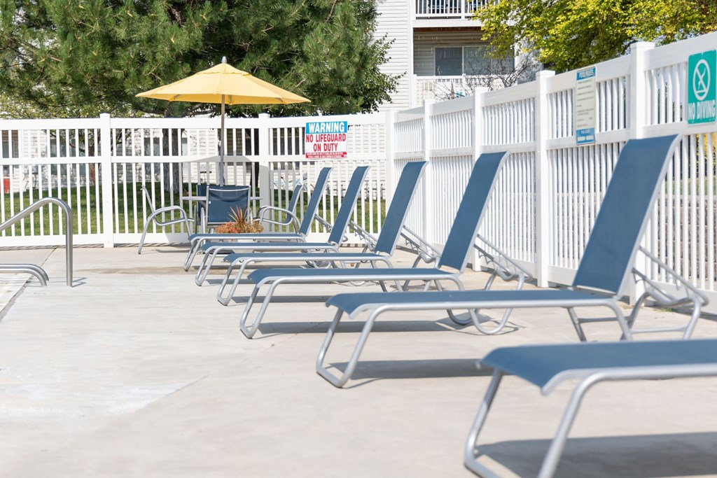 a row of chairs and an umbrella in front of a pool