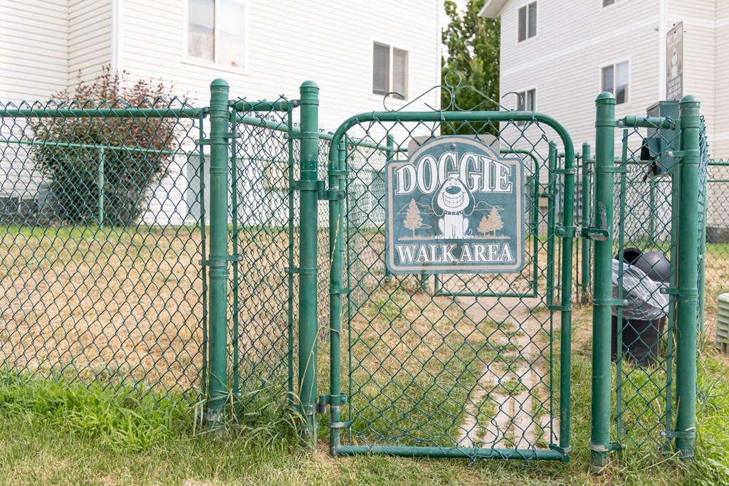 a dog walking area sign on a chain link fence