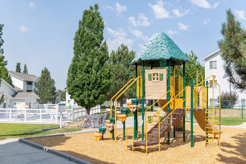 a playground with a yellow swing set and a gazebo