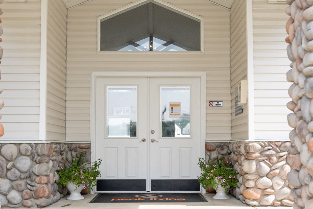the front door of a house with white doors and a stone wall