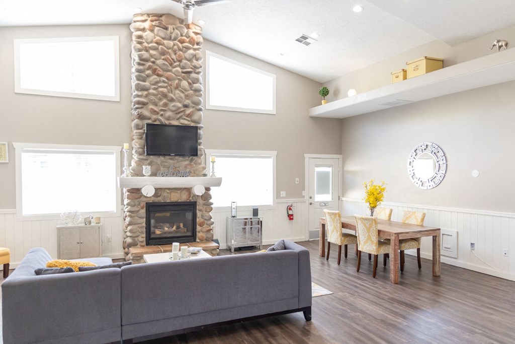 a living room with a stone fireplace and a dining room table