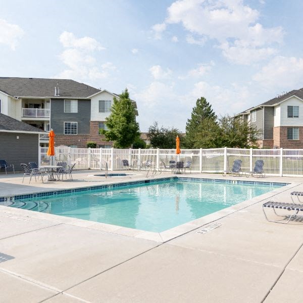 a swimming pool with chairs and umbrellas in front of a building