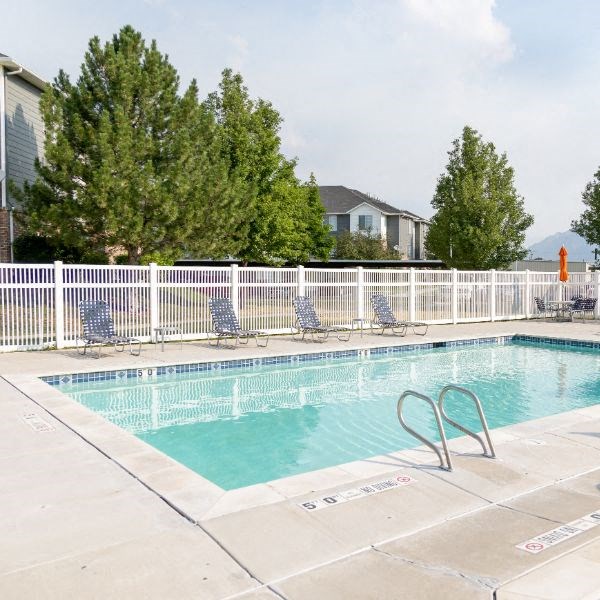 a swimming pool with chairs and a fence around it