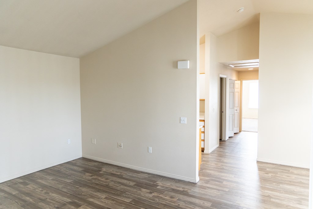 an empty living room with white walls and wood floors