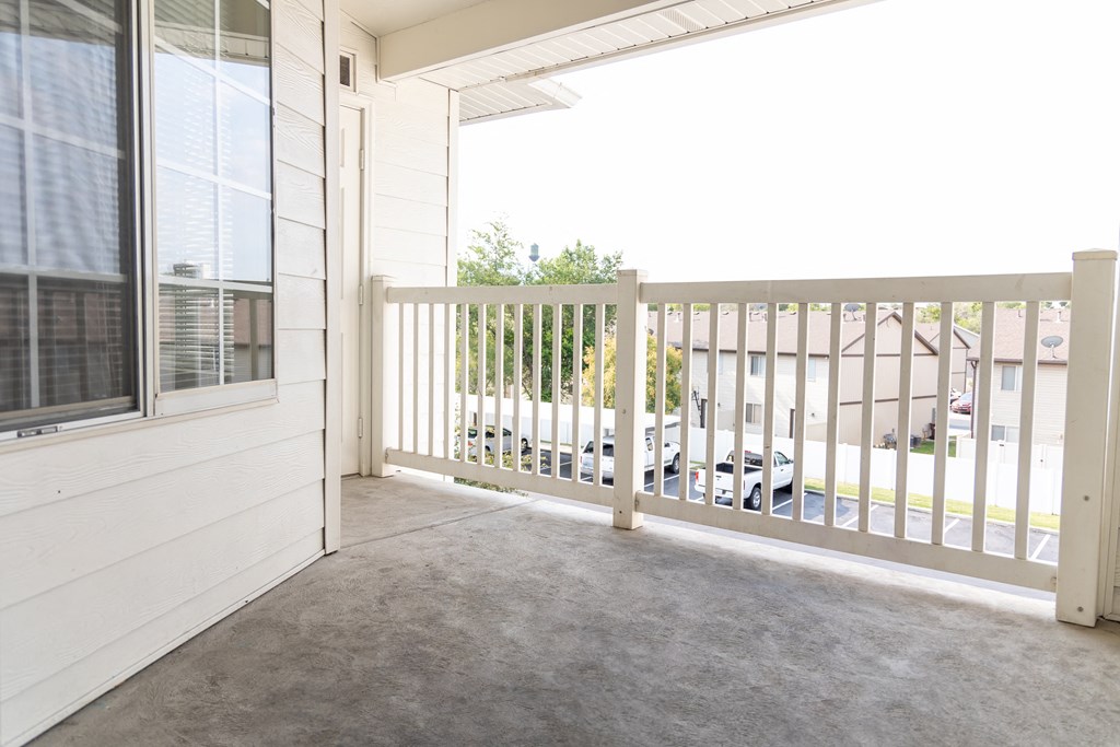 a covered porch with a white railing and a white house