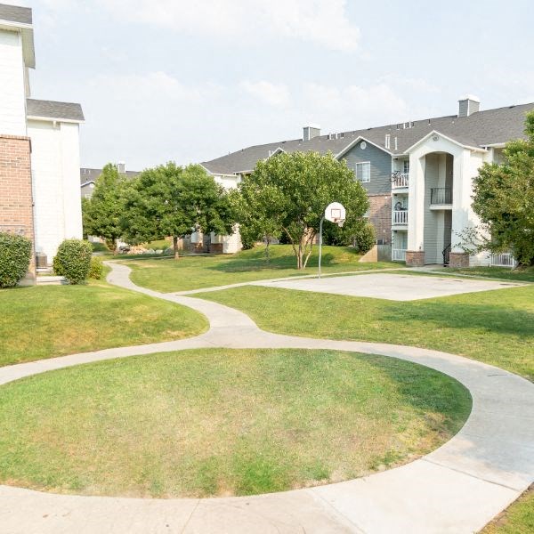 an apartment building with a basketball court and sidewalk