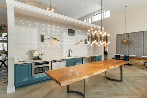 A modern kitchen with a long wooden table and blue cabinets.