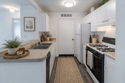 A kitchen with a stove, sink, and refrigerator.