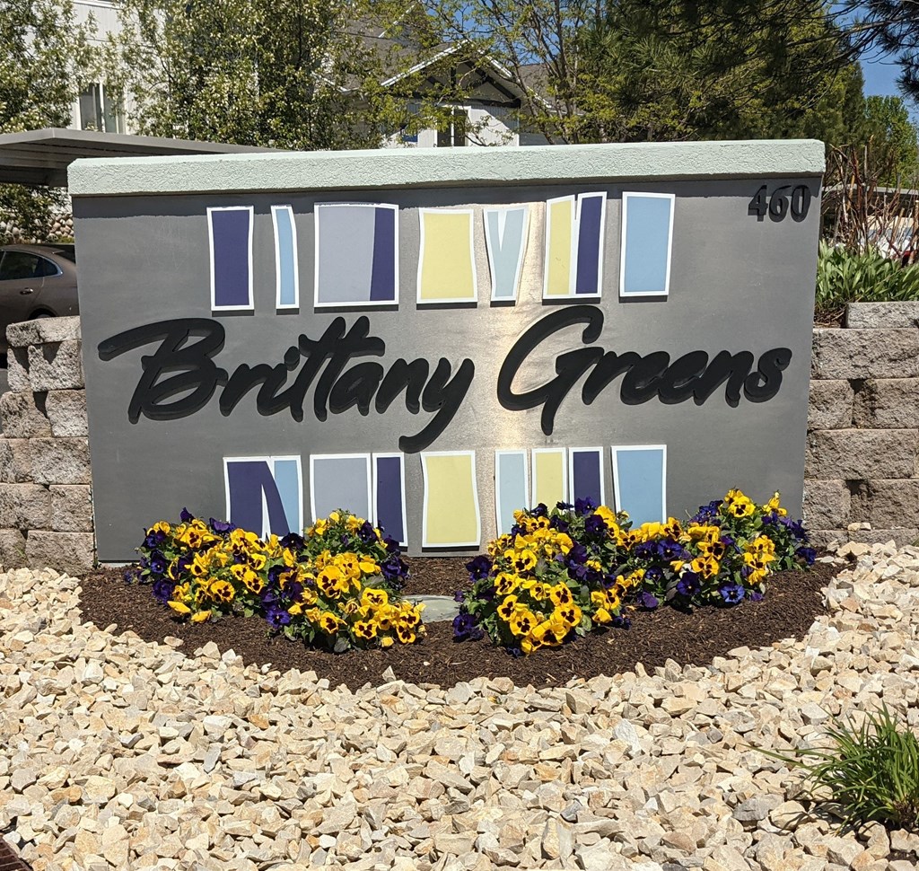 a sign in front of a garden of flowers