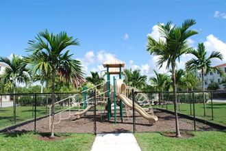 a playground with slides in a park with palm trees