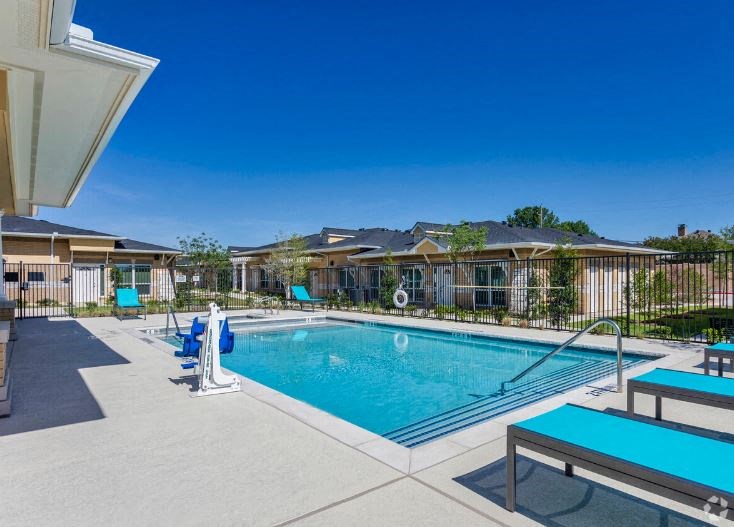 a swimming pool with blue chairs and a resort style building