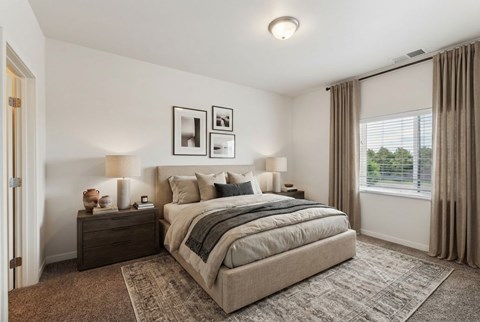 A bedroom with a large bed and a window with curtains.