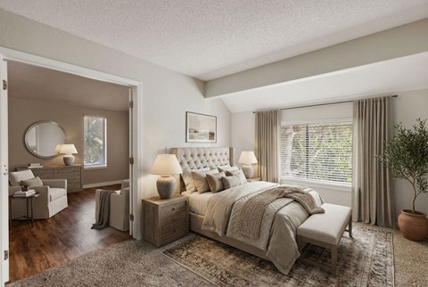 A bedroom with a large bed and a dressing table with a mirror.
