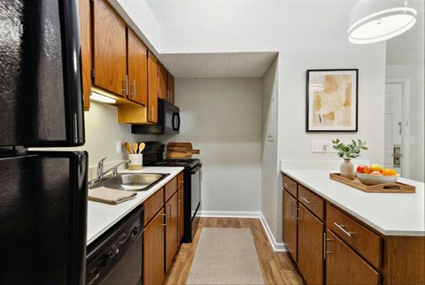 A kitchen with a black fridge and wooden cabinets.