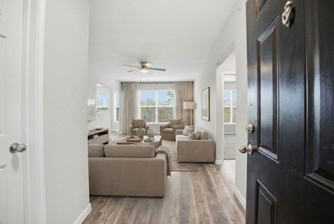 A living room with a brown couch and a ceiling fan.