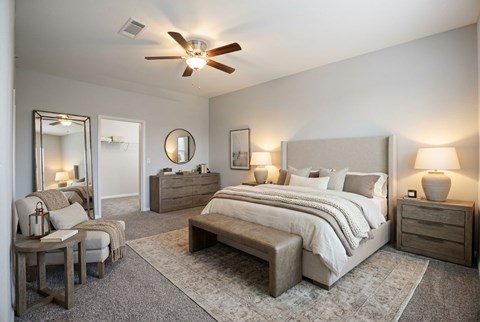 A bedroom with a large bed, a chair, and a dresser.