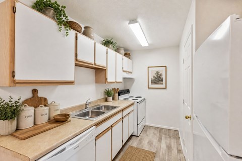 A kitchen with white cabinets and a wooden cutting board on the counter.