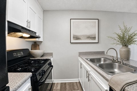 A small kitchen with a black stove and white cabinets.
