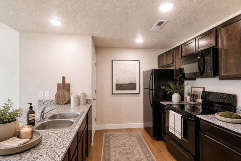 A kitchen with a black refrigerator and wooden cabinets.