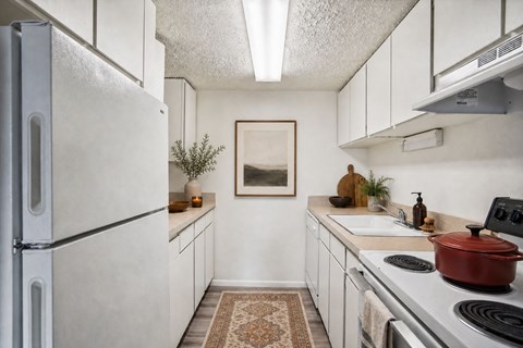 A kitchen with a refrigerator, stove, and a rug on the floor at The Morgan Apartments, Layton, Utah