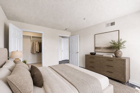 A bedroom with a large bed and a dresser with a mirror above it.