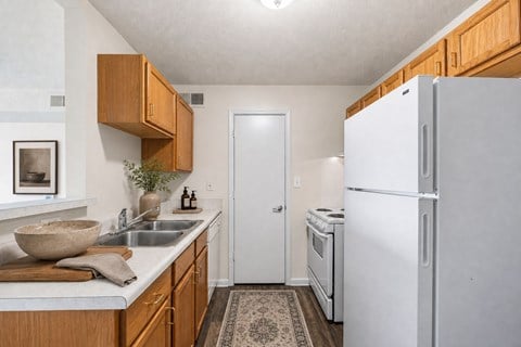 A kitchen with a white refrigerator and wooden cabinets.