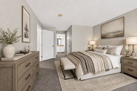 A bedroom with a large bed and a dresser with a vase on top.