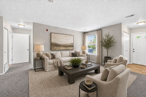 A living room with a grey carpet and a large painting on the wall.