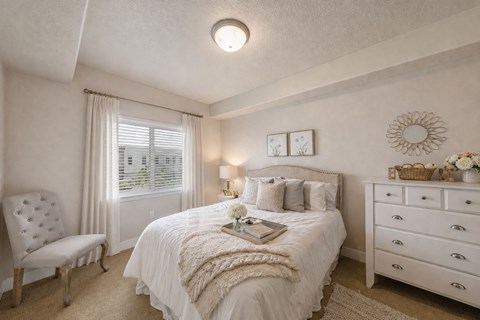 Bedroom with tufted chair and white dresser at The Beckstead Apartments, South Jordan
