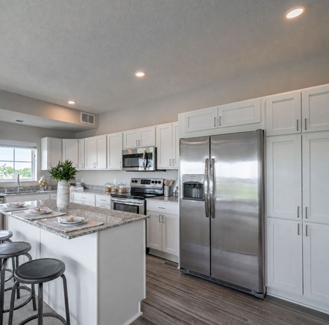 A modern kitchen with white cabinets and a stainless steel refrigerator.
