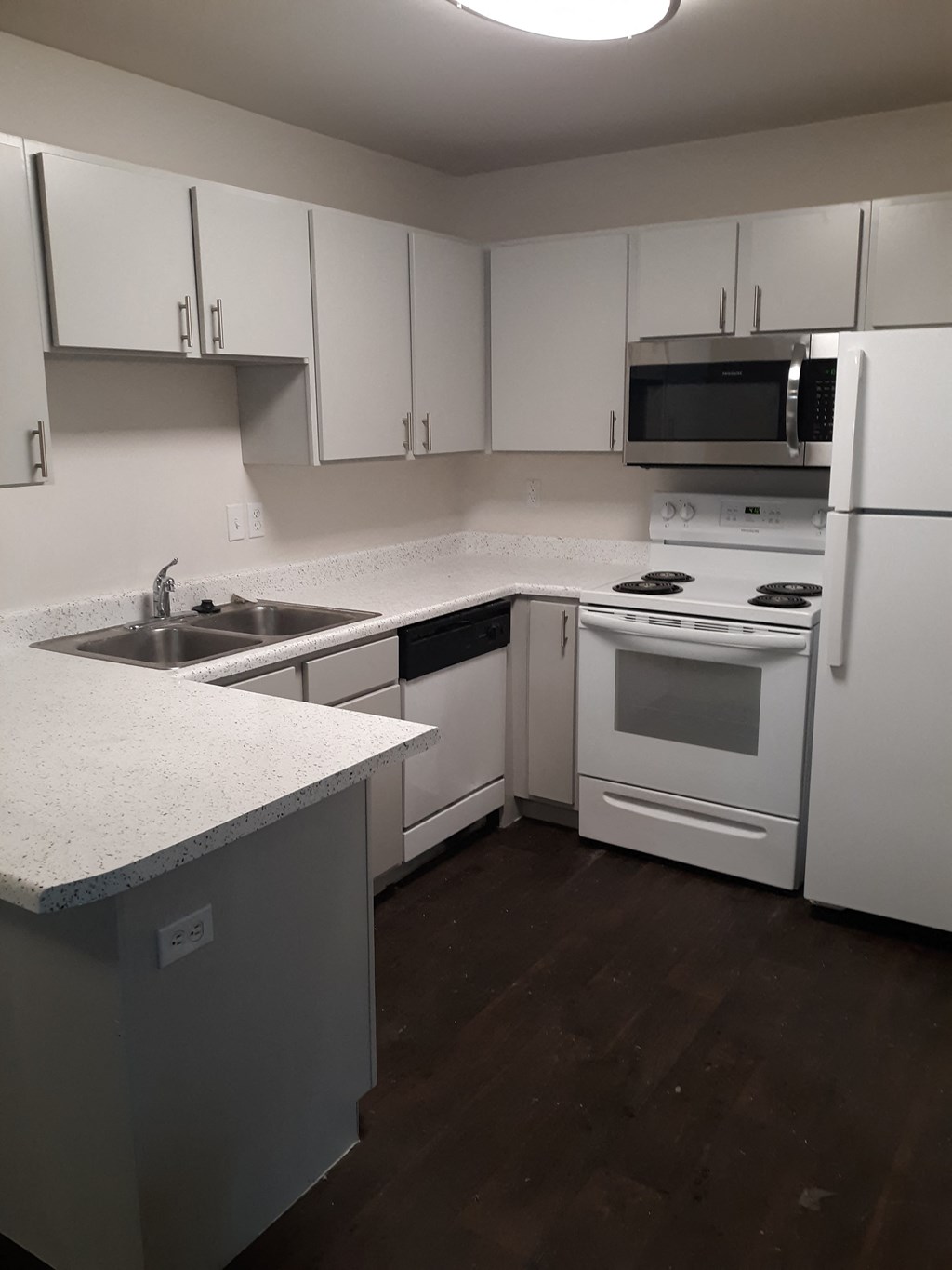 an empty kitchen with white appliances and white cabinets