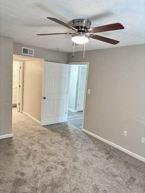 A room with a ceiling fan and carpeted floor.