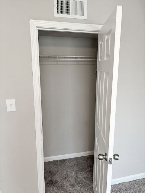 A white door is open to a room with a carpeted floor.