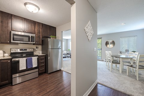 a kitchen with stainless steel appliances and a dining room with a table and chairs