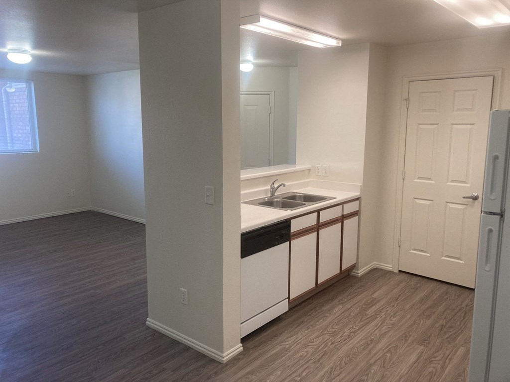 an empty kitchen with white cabinets and a sink
