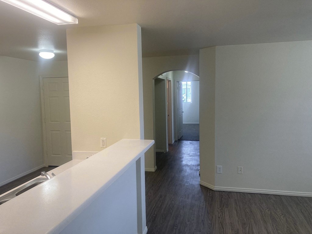 a kitchen and living room with white walls and wood flooring