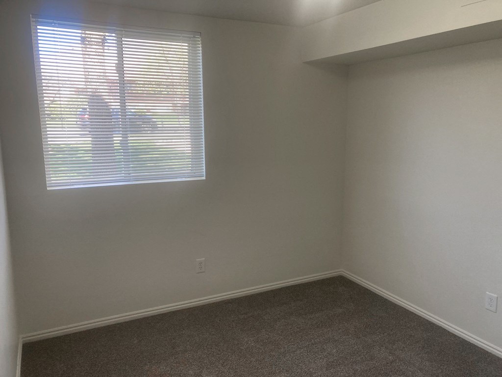 an empty room with a window and a carpet