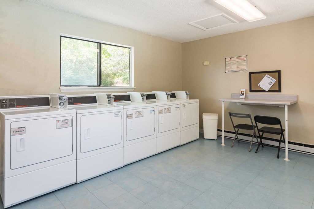the laundry room is equipped with washers and dryers and a table with chairs