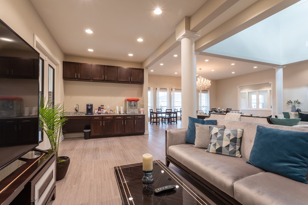 A modern living room with a large couch and a kitchen area.